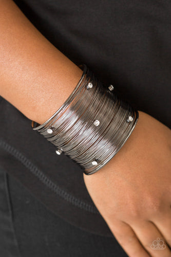 Shimmery gunmetal wires wrap back and forth along a gunmetal frame, creating a bold cuff. Glassy white rhinestones are sprinkled across the dramatic cuff for a glamorous finish.  Sold as one individual bracelet.  Always nickel and lead free.