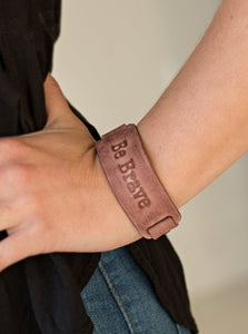 Brushed in a rustic finish, a brown leather band is stamped in the phrase, “Be Brave” for an inspiring finish. Features an adjustable snap closure.  Sold as one individual bracelet.