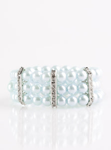 Classic blue pearls are threaded along elastic stretchy bands, creating colorful layers across the wrist. Encrusted in glittery white rhinestones, shimmery silver frames fit around the pearl strands, joining the bracelets.  Sold as one individual bracelet.