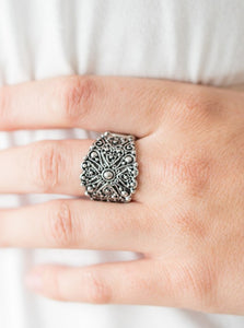 Brushed in an antiqued shimmer, silver filigree climbs the finger, swirling into a rustic floral frame. Features a stretchy band for a flexible fit.  Sold as one individual ring.   