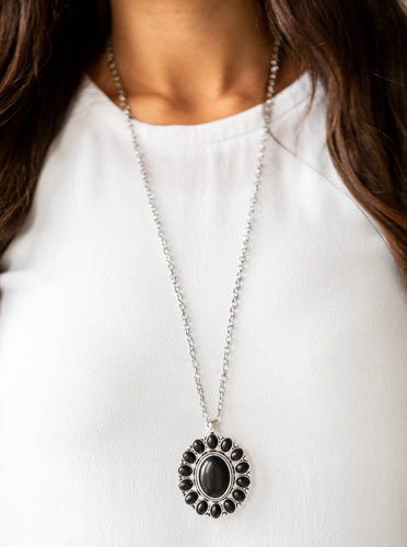 Radiating with black stone accents, a dramatic floral pendant swings from the bottom of a lengthened silver chain for a seasonal look. Features an adjustable clasp closure.  Sold as one individual necklace. Includes one pair of matching earrings.