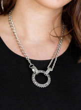 Load image into Gallery viewer, Featuring mismatched silver chains, a studded silver pendant has been encrusted in glittery hematite rhinestones and hung below the collar for a dramatic industrial look. Features an adjustable clasp closure.  Sold as one individual necklace. Includes one pair of matching earrings.