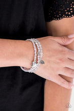 Load image into Gallery viewer, An array of glassy and polished gray beads are threaded along stretchy bands. Infused with silver accents, a collection of silver heart charms and a bead spelling out the word, &quot;love&quot;, adorn the beaded strands for a romantic finish.  Sold as one set of three bracelets.  Always nickel and lead free.