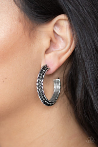 The top half of a bold silver frame is encrusted in hematite rhinestones, giving way to glistening silver studs for an edgy finish. Earring attaches to a standard post fitting. Hoop measures approximately 1 1/4