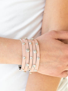 Dotted with glassy white rhinestones, a thick pink leather band has been spliced into five glittery strands around the wrist for a sassy look. Features an adjustable snap closure.  Sold as one individual bracelet.  