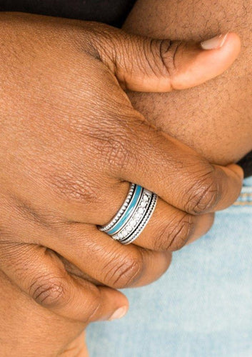 A shiny blue strip of color runs along the bottom of a row of glassy white rhinestones. Infused with silver textures, the mismatched details coalesce into one thick band across the finger. Features a stretchy band for a flexible fit.  Sold as one individual ring.  Always nickel and lead free.