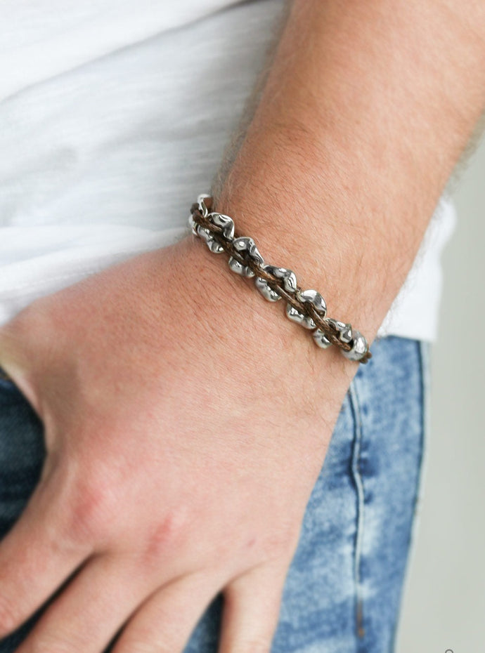 Shiny brown cording weaves through hammered silver beads around the wrist for an urban look. Features an adjustable sliding knot closure.  Sold as one individual bracelet.