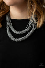 Load image into Gallery viewer, Countless layers of neutral gray seed beads drape below the collar. Additional strands of gray seed beads wrap around the center of the layers, creating two bulky rows for a seasonal flair. Features an adjustable clasp closure.  Sold as one individual necklace. Includes one pair of matching earrings.  Always nickel and lead free.