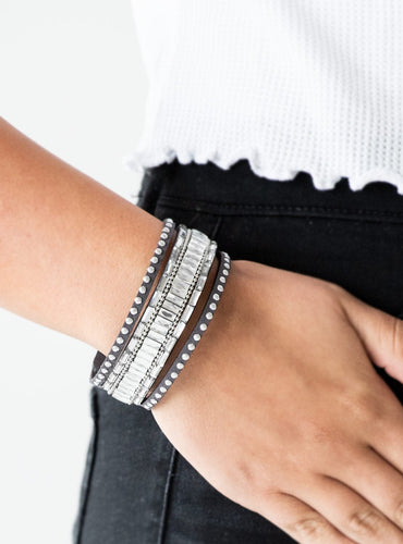Shiny silver studs, dainty silver ball chains, and edgy white emerald-cut rhinestones race along a spliced black suede band for a rock star look. Features an adjustable snap closure.  Sold as one individual bracelet.