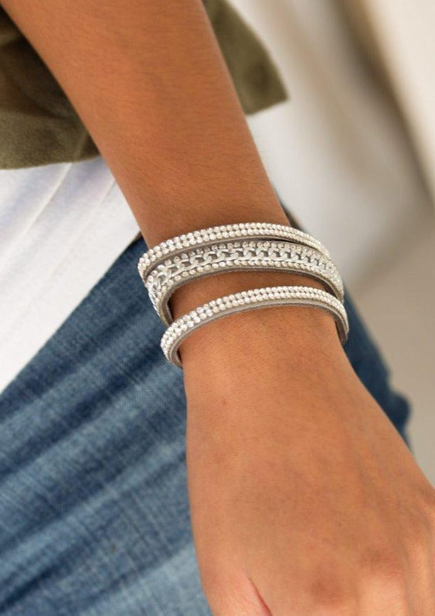 Rows of glassy white rhinestones and a shimmery silver chain are encrusted along gray suede bands for a sassy look. Features an adjustable snap closure.  Sold as one individual bracelet.  Always nickel and lead free.