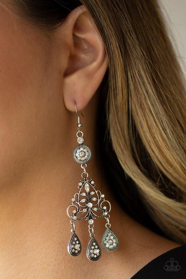 Sold as one pair of earrings.White rhinestone encrusted silver teardrops drip from the bottom of an ornate silver frame. Dusted in rhinestones, the frilly frame swings from the bottom of a round white rhinestone fitting, creating an elegant chandelier. Earring attaches to a standard fishhook fitting.  Sold as one pair of earrings.  Always nickel and lead free.