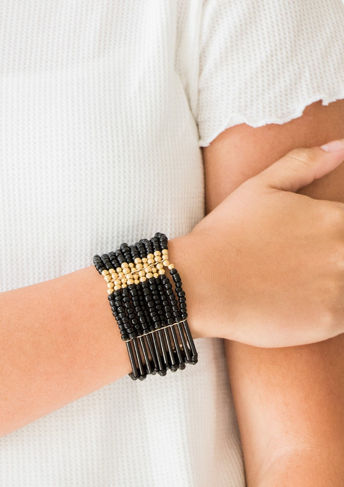 Joined together with metallic fittings, black seed beads are threaded along stretchy elastic bands. Sections of gold beads are sprinkled along the edgy layers, adding hints of shimmer to the seasonal palette.  Sold as one individual bracelet.