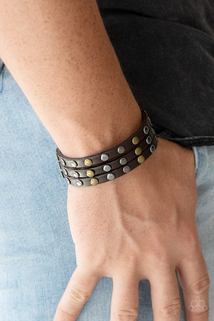 Split into three strands, antiqued brass and gunmetal beads are studded along the front of a brown leather band for a rustic look. Features an adjustable snap closure.  Sold as one individual bracelet.  Always nickel and lead free.