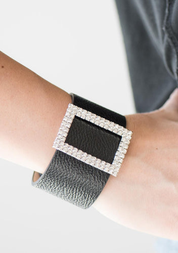 Two rows of dazzling white rhinestones coalesce into a rectangular frame. The glittery frame is threaded along a band of black leather, creating a stunning centerpiece. Features an adjustable snap closure.  Sold as one individual bracelet.  