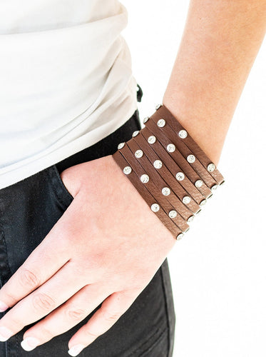 A thick brown leather band has been spliced into numerous brown strands. Featuring sleek silver frames, glittery white rhinestones are sprinkled across the leather bands for a sassy finish. Features an adjustable snap closure.  Sold as one individual bracelet.  