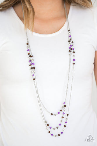 Dainty silver, purple, and wooden beads trickle along three shimmery silver chains, creating colorful layers across the chest. Features an adjustable clasp closure.  Sold as one individual necklace. Includes one pair of matching earrings. Always nickel and lead free.