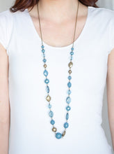 Load image into Gallery viewer, Varying in opacity and shape, a collection of polished, pearly, and glassy blue beads link with antiqued brass beads across the chest for a whimsical finish. Features an adjustable clasp closure.  Sold as one individual necklace. Includes one pair of matching earrings.  Always nickel and lead free.