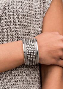 Finished in antiqued silver, a thick silver cuff is filled with rows of dotted texture and bordered by a raised linear frame, resulting in a bold statement piece.