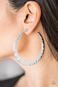 Brushed in a high-sheen finish, a delicately hammered silver hoop curls around the ear for a fierce look. Earring attaches to a standard post fitting. Hoop measures 2 1/2" in diameter.  Sold as one pair of hoop earrings.  Always nickel and lead free.