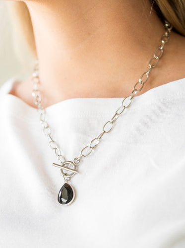 A faceted black teardrop gem swings from the bottom of a shimmery silver chain, creating a classic pendant below the collar. Features a toggle closure.  Sold as one individual necklace. Includes one pair of matching earrings.  