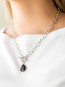A faceted black teardrop gem swings from the bottom of a shimmery silver chain, creating a classic pendant below the collar. Features a toggle closure.  Sold as one individual necklace. Includes one pair of matching earrings.  