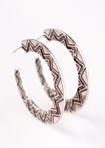 A silver ribbon is etched in a radiant sunburst pattern. Highlighted with fiery red accents.A silver ribbon is etched in a radiant sunburst pattern. Highlighted with fiery red accents, the shimmery display falls from the ear in a trendy tribal fashion. Earring attaches to a standard post fitting. Hoop measures 1 5/8” in diameter.  Sold as one pair of hoop earrings.