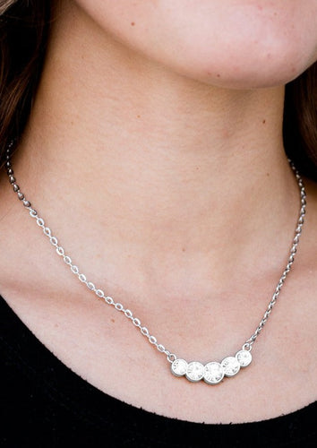 Pressed in glistening silver frames, glittery white rhinestones join into a subtlety bowing pendant below the collar for a refined fashion. Features an adjustable clasp closure.  Sold as one individual necklace. Includes one pair of matching earrings.