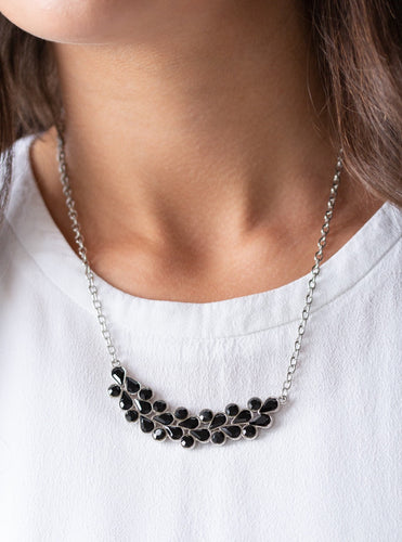 A collection of round and teardrop black rhinestones coalesce into a bowing silver pendant below the collar for a refined look. Features an adjustable clasp closure.  Sold as one individual necklace. Includes one pair of matching earrings.  
