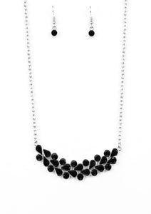 A collection of round and teardrop black rhinestones coalesce into a bowing silver pendant below the collar for a refined look. Features an adjustable clasp closure.  Sold as one individual necklace. Includes one pair of matching earrings.