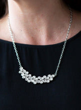 Load image into Gallery viewer, A collection of round and teardrop white rhinestones coalesce into a bowing silver pendant below the collar for a refined look. Features an adjustable clasp closure.  Sold as one individual necklace. Includes one pair of matching earrings.