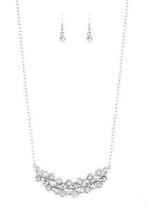 A collection of round and teardrop white rhinestones coalesce into a bowing silver pendant below the collar for a refined look. Features an adjustable clasp closure.  Sold as one individual necklace. Includes one pair of matching earrings.