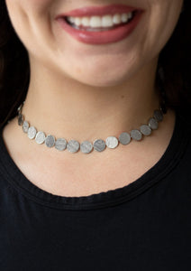 Delicately scratched in linear shimmer, dainty silver discs link around the neck for a blinding metallic look. Features an adjustable clasp closure.  Sold as one individual choker necklace. Includes one pair of matching earrings.