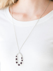 Varying in size, an array of glittery white and purple rhinestones are encrusted along a shimmery silver hoop. The sparkling pendant swings from the bottom of an elongated silver chain for a glamorous finish. Features an adjustable clasp closure.  Sold as one individual necklace. Includes one pair of matching earrings.