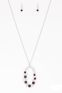Varying in size, an array of glittery white and purple rhinestones are encrusted along a shimmery silver hoop. The sparkling pendant swings from the bottom of an elongated silver chain for a glamorous finish. Features an adjustable clasp closure.  Sold as one individual necklace. Includes one pair of matching earrings.