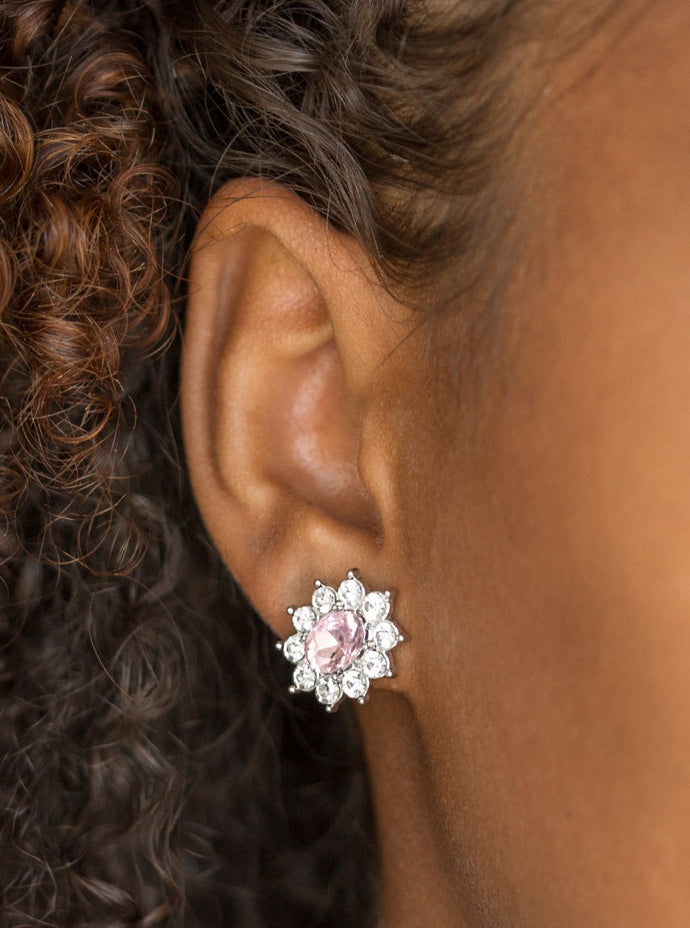 Glassy white rhinestones spin around an oval pink rhinestone center, coalescing into a refined frame. Earring attaches to a standard post fitting.  Sold as one pair of post earrings.   