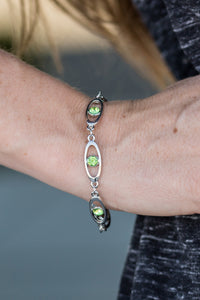 Sparkling green rhinestones adorn the center of glistening silver frames. The oval frames link around the wrist, creating a colorfully, refined palette. Features an adjustable clasp closure.  Sold as one individual bracelet.  Always nickel and lead free.