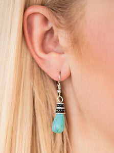 Capped in a studded silver frame, a refreshing turquoise stone teardrop drips from the ear for a seasonal look. Earring attaches to a standard fishhook fitting.  Sold as one pair of earrings.