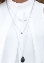 Load image into Gallery viewer, A textured silver bar is suspended horizontally from the uppermost chain above two stone pendants. A dainty black stone hangs from the center most layer as a black stone teardrop swings from the lowermost chain for a bold artisanal finish. Features an adjustable clasp closure.  Sold as one individual necklace. Includes one pair of matching earrings. 