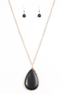 Chiseled into a tranquil teardrop, a smooth black stone swings from the bottom of a glistening gold chain, creating a dramatically earthy pendant. Features an adjustable clasp closure.  Sold as one individual necklace. Includes one pair of matching earrings.