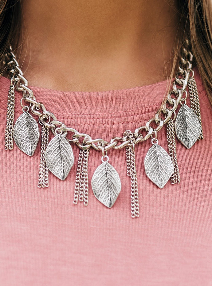 Decorated in lifelike textures, glistening silver leaves swing from the bottom of a bold silver chain. Infused with sections of silver chain tassels, the leafy fringe drapes below the collar for a seasonal look. Features an adjustable clasp closure.  Sold as one individual necklace. Includes one pair of matching earrings.