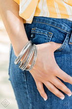 Load image into Gallery viewer, Featuring an array of floral and tribal-inspired patterns, a collection of mismatched silver bangles slide along the wrist for a seasonal look.