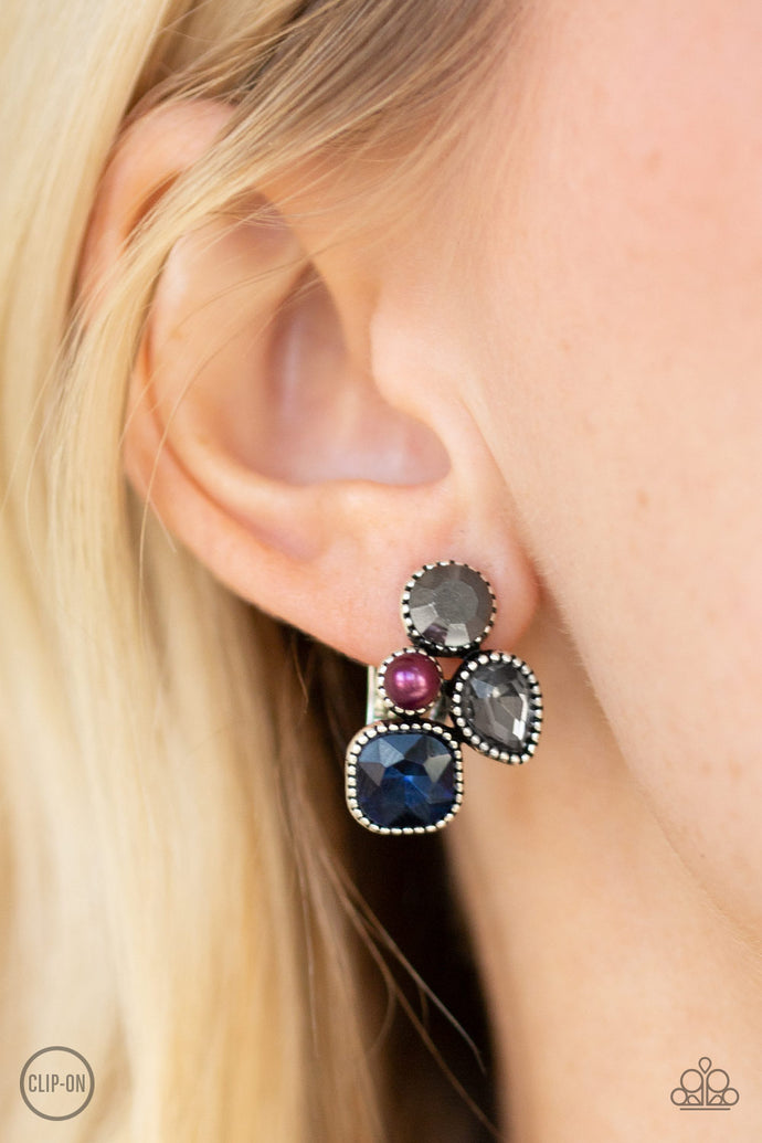 Infused with a dainty purple pearl, mismatched blue, smoky, and hematite rhinestones coalesce into a glittery frame. Earring attaches to a standard clip-on fitting.  Sold as one pair of clip-on earrings.  Always nickel and lead free.  .