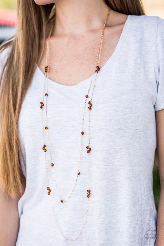 Brown crystal-like beads trickle along two strands of shimmery gold chain, creating glittery accents across the chest. Features an adjustable clasp closure.  Sold as one individual necklace. Includes one pair of matching earrings.