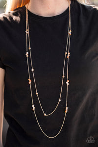 Golden crystal-like beads trickle along two strands of shimmery gold chain, creating glittery accents across the chest. Features an adjustable clasp closure.  Sold as one individual necklace. Includes one pair of matching earrings.  Always nickel and lead free.