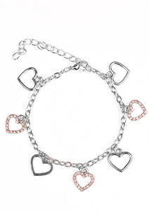 Dainty silver heart charms dangle from the wrist. Glittery pink rhinestones are sprinkled along alternating hearts for a refined finish. Features an adjustable clasp closure.  Sold as one individual bracelet..
