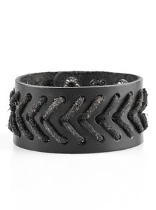 Distressed black leather cording is stitched across the front of a thick leather band for a rugged look. Features an adjustable snap closure.  Sold as one individual bracelet.