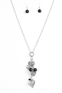 Filigree filled heart charms trickle along a silver chain, creating a whimsically stacked pendant. Polished black beading trickles between the hearts for a colorful finish. Features an adjustable clasp closure.  Sold as one individual necklace. Includes one pair of matching earrings.