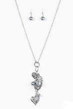 Load image into Gallery viewer, Filigree filled heart charms trickle along a silver chain, creating a whimsically stacked pendant. Silver pearlescent beading trickles between the hearts for a colorful finish. Features an adjustable clasp closure.  Sold as one individual necklace. Includes one pair of matching earrings.