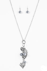 Filigree filled heart charms trickle along a silver chain, creating a whimsically stacked pendant. Silver pearlescent beading trickles between the hearts for a colorful finish. Features an adjustable clasp closure.  Sold as one individual necklace. Includes one pair of matching earrings.