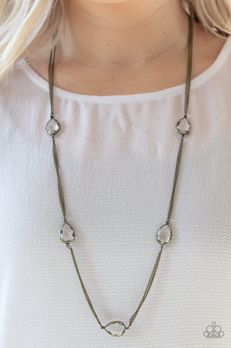 Glassy white teardrops attach to sections of antiqued brass chain across the chest, creating a refined display. Features an adjustable clasp closure.  Sold as one individual necklace. Includes one pair of matching earrings.  Always nickel and lead free.